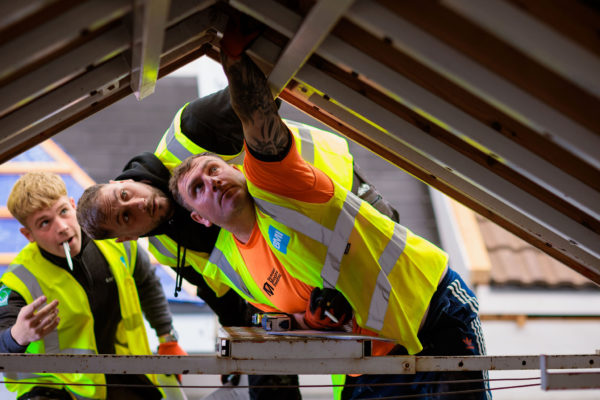 Nathan Binnall assessing a roofing model at the BMI Apprentice of the Year event, diagnosing potential issues alongside other finalists.